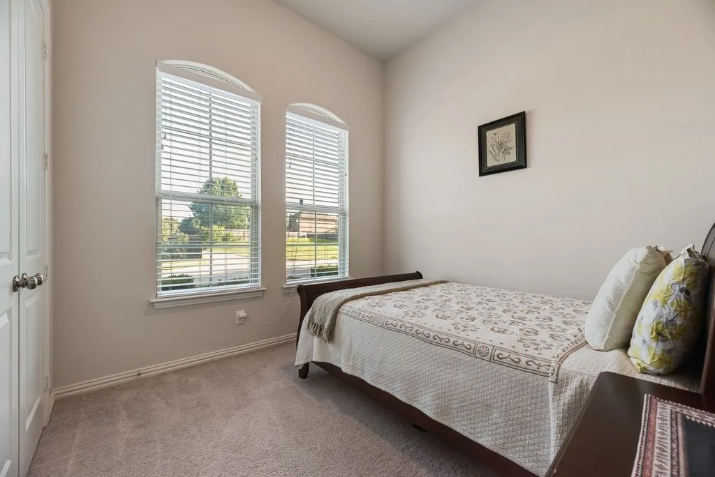 Room featuring two arched windows with blinds, neutral-toned walls, and carpet flooring