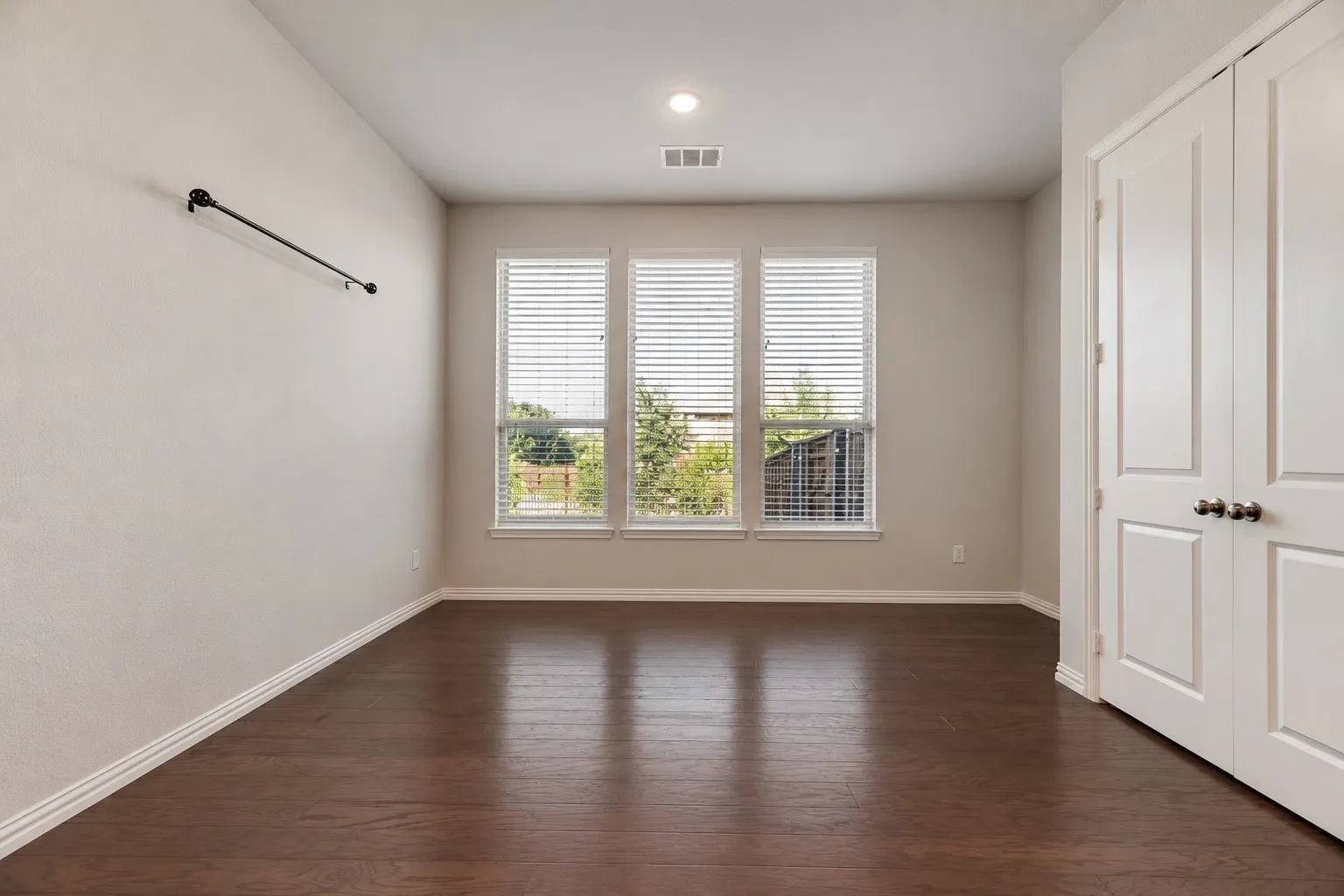 Rich wood-finish flooring, a contemporary fireplace with a wood mantle, a ceiling fan, recessed lighting, and a kitchen featuring a central island with a quartz countertop