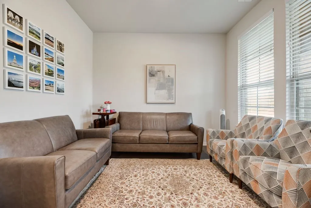 Bright living space featuring neutral wall tones, large windows with horizontal blinds, and recessed lighting