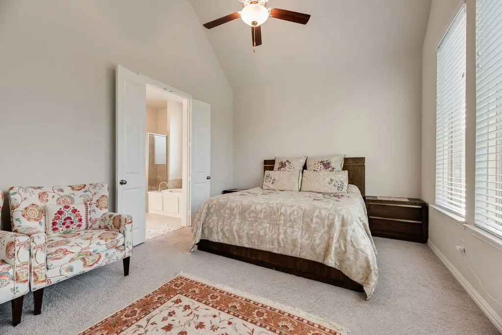 Carpeted interior space featuring a vaulted ceiling and a ceiling fan