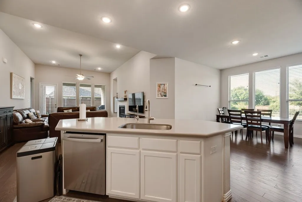 Kitchen island with a stainless steel sink, integrated dishwasher, and white cabinetry