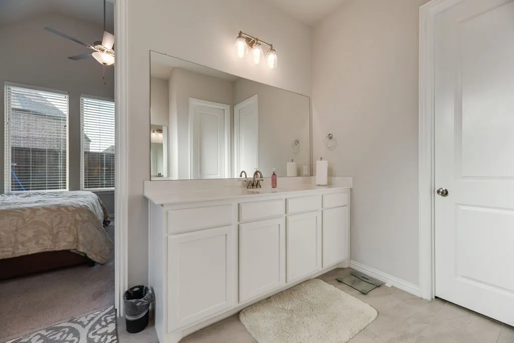 Dual vanity with a white countertop and undermount sinks, featuring a large mirror and three-light fixture
