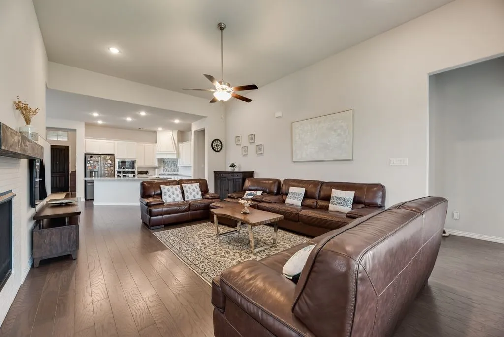 Expansive living area featuring wood-finish flooring, vaulted ceilings, and recessed lighting