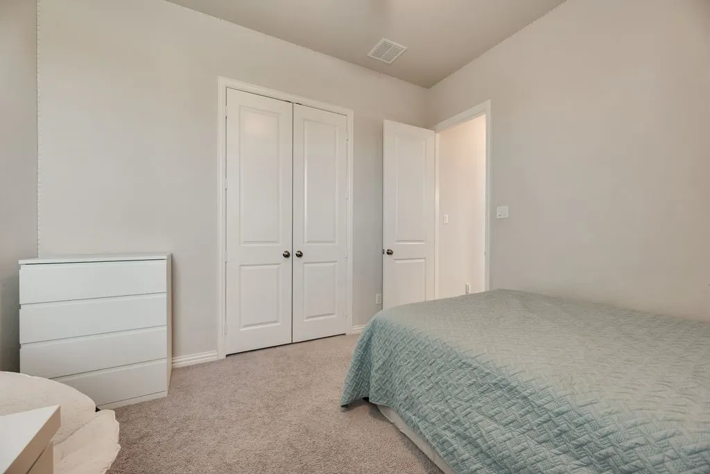 Carpeted room featuring light gray walls, white baseboards, and a white double-door closet with dark hardware