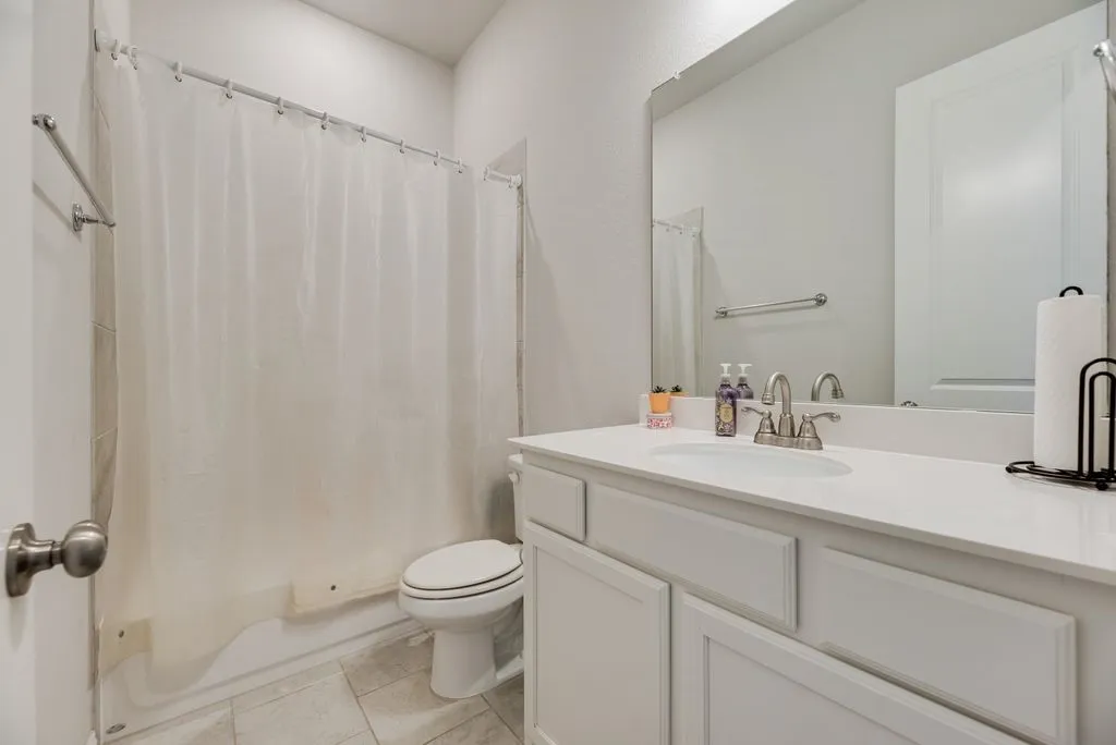 Bathroom featuring a built-in vanity with white cabinetry, an integrated sink, and a large wall-mounted mirror