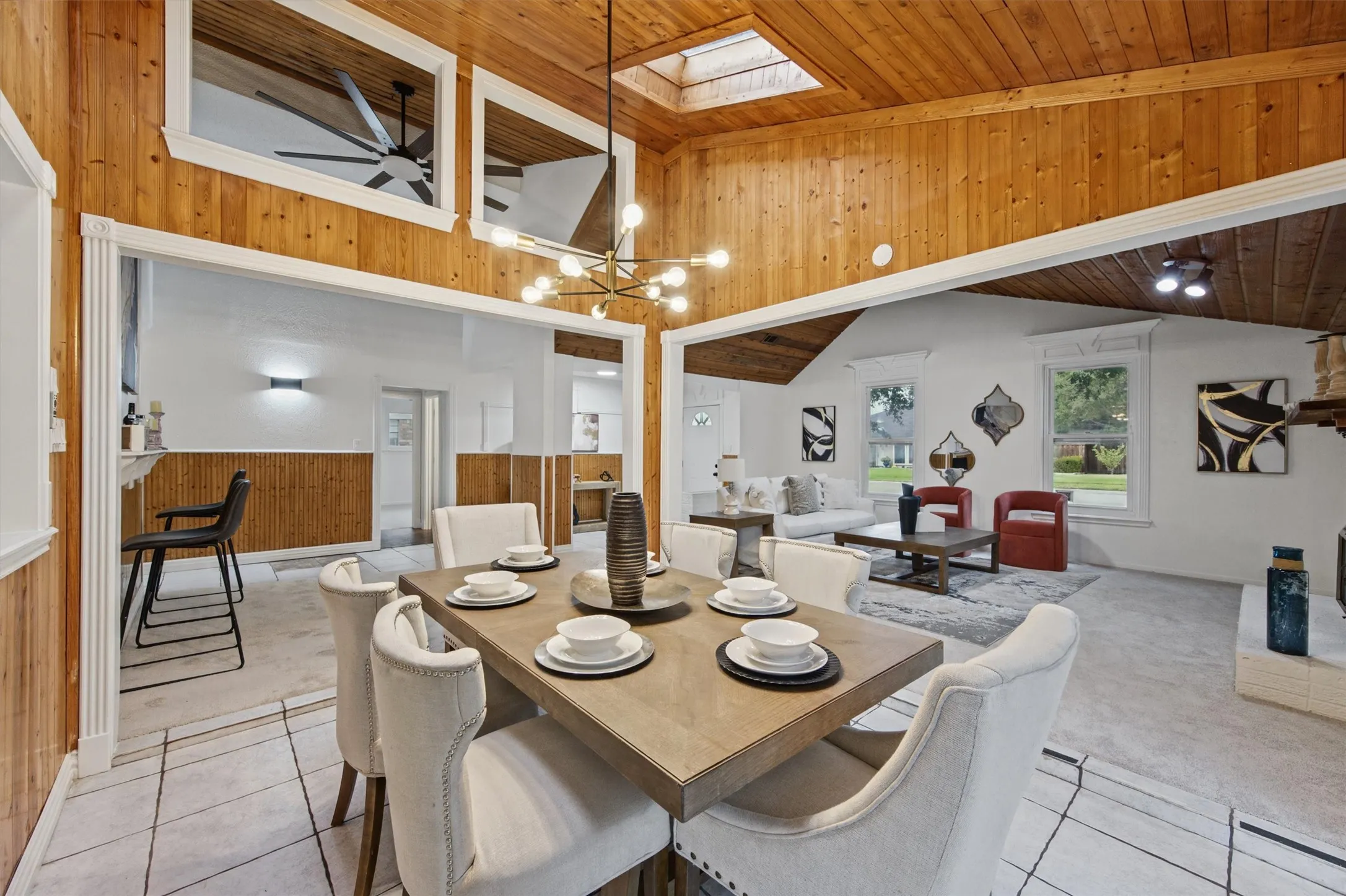 Wood-paneled vaulted ceiling with skylight, modern chandelier, tile flooring, and wood-paneled walls