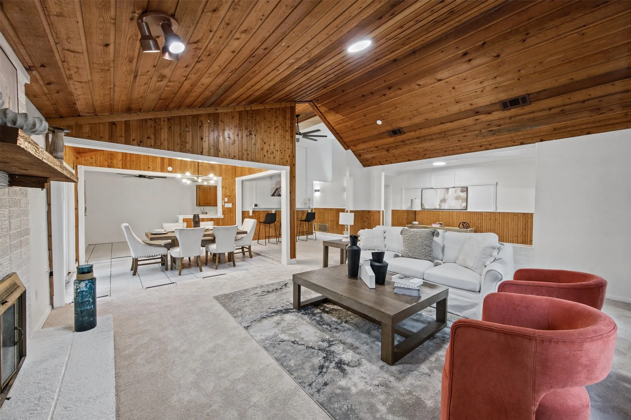 Vaulted wood-paneled ceiling with recessed lighting, stone-clad fireplace, and wood-finish accent walls