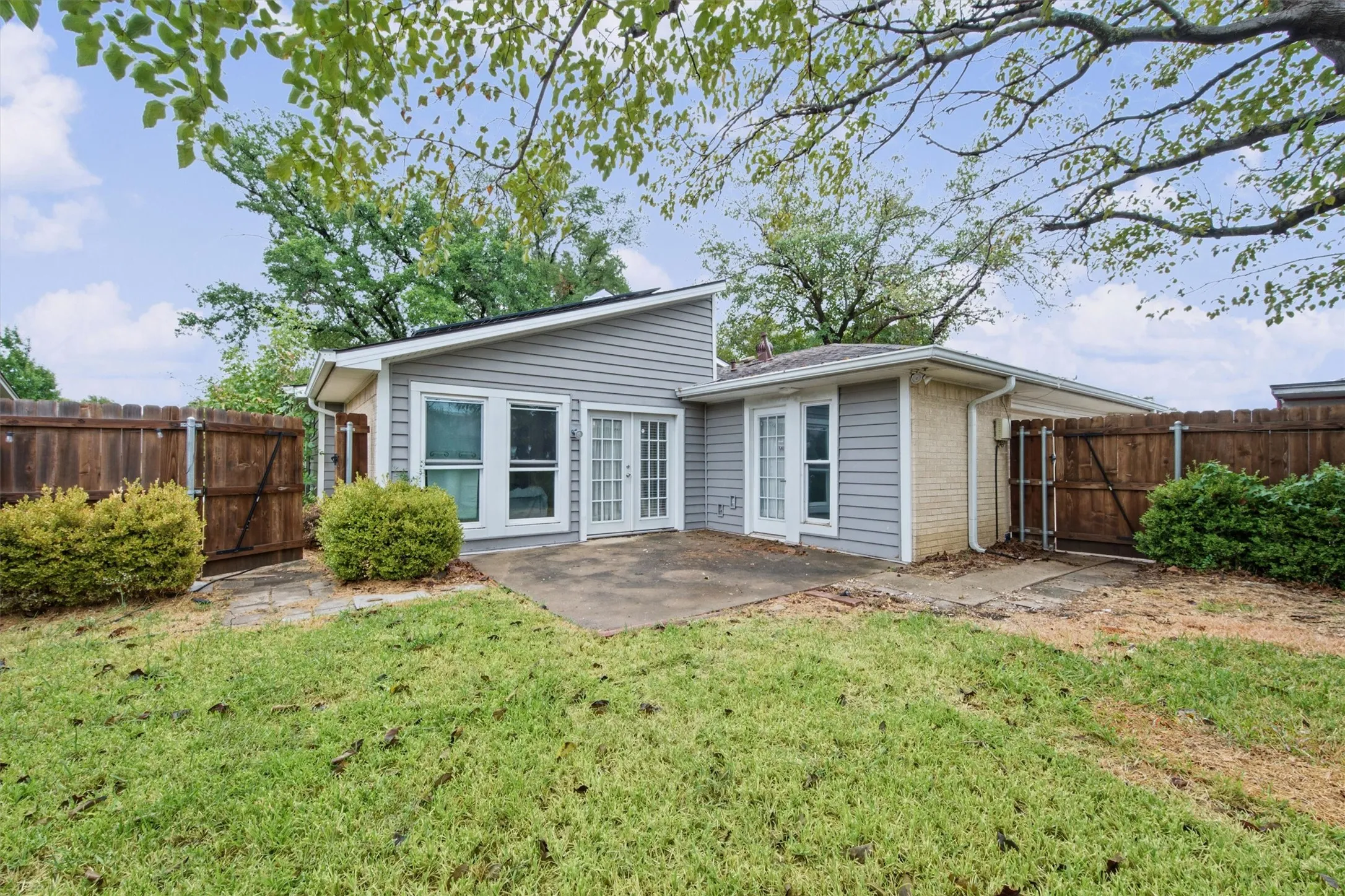 Private backyard featuring a concrete patio, wood fencing, and mature landscaping