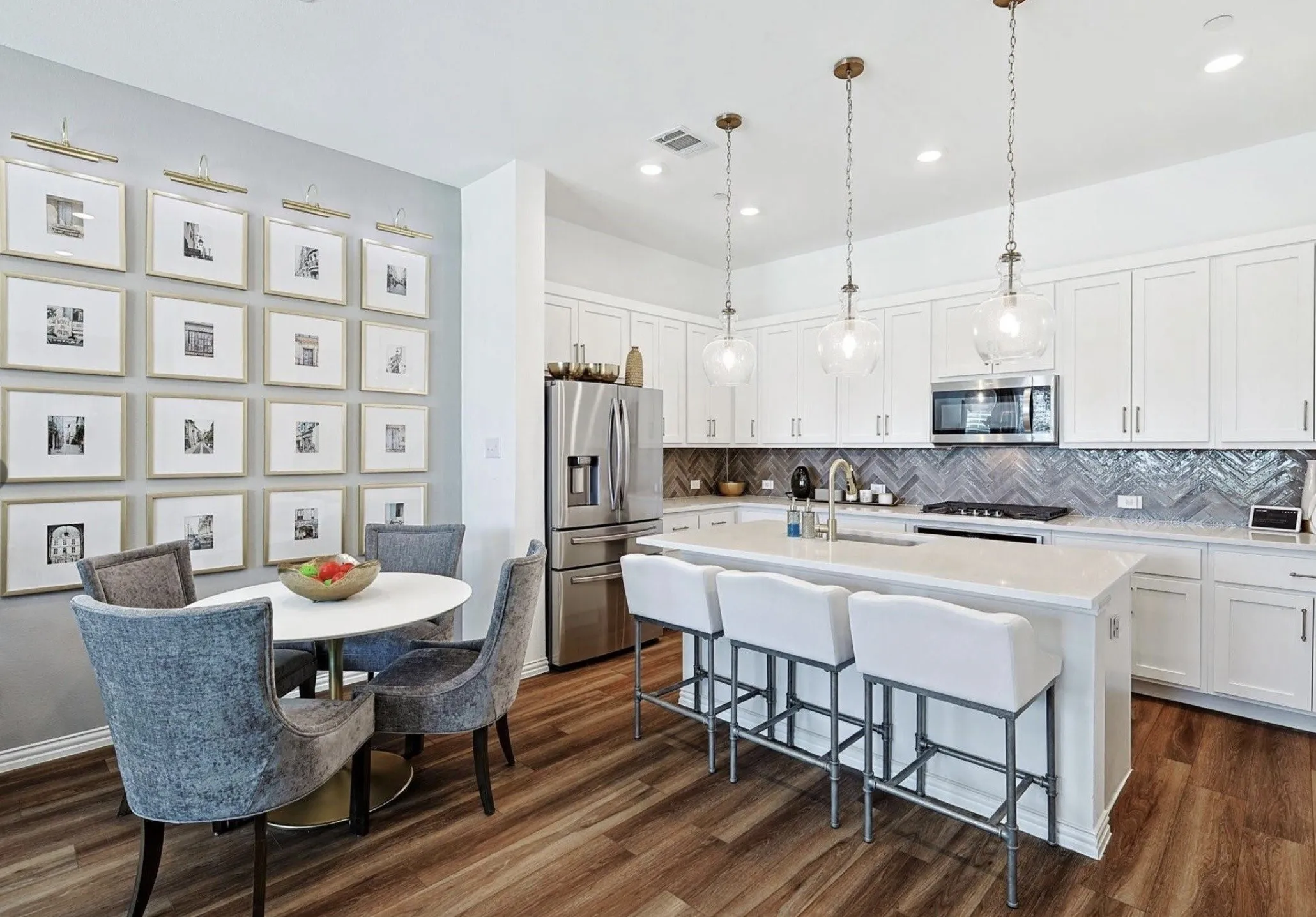 Gourmet kitchen with white shaker cabinetry, stainless steel appliances, herringbone tile backsplash, and a large center island with seating
