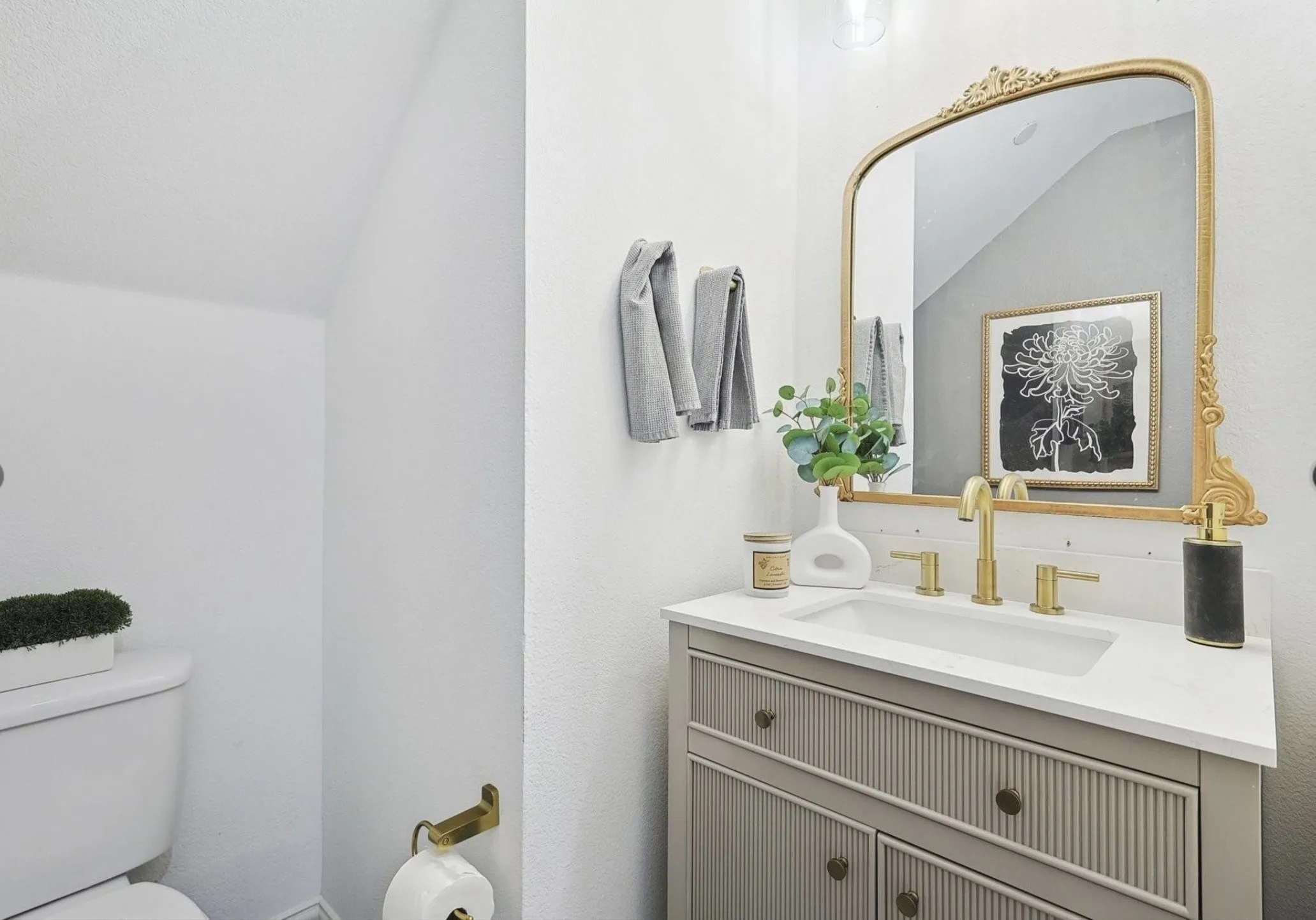 Vanity with integrated rectangular sink, gold-finish faucet, and coordinating ornate mirror