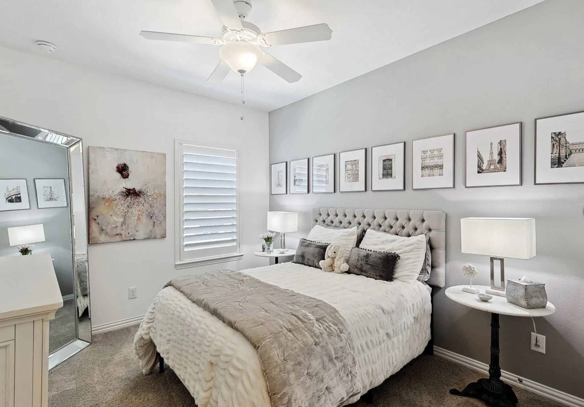 Carpeted flooring, window with plantation shutters, ceiling fan with integrated lighting, and a tufted upholstered headboard