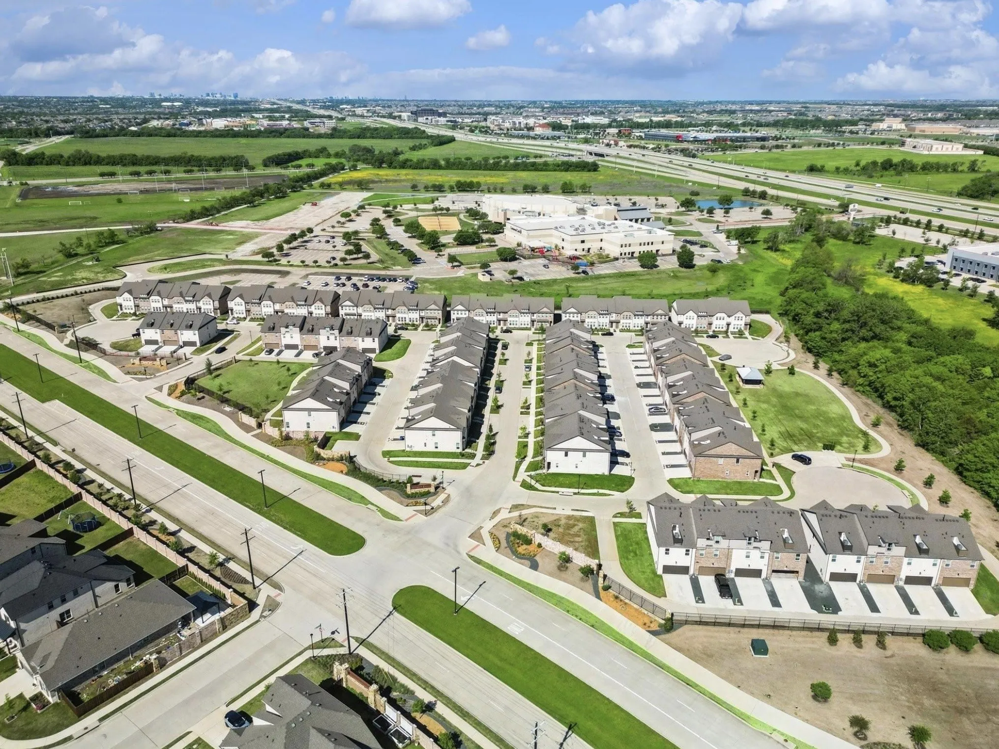 Newly constructed townhome community with attached garages, surrounded by developed roads and extensive green spaces