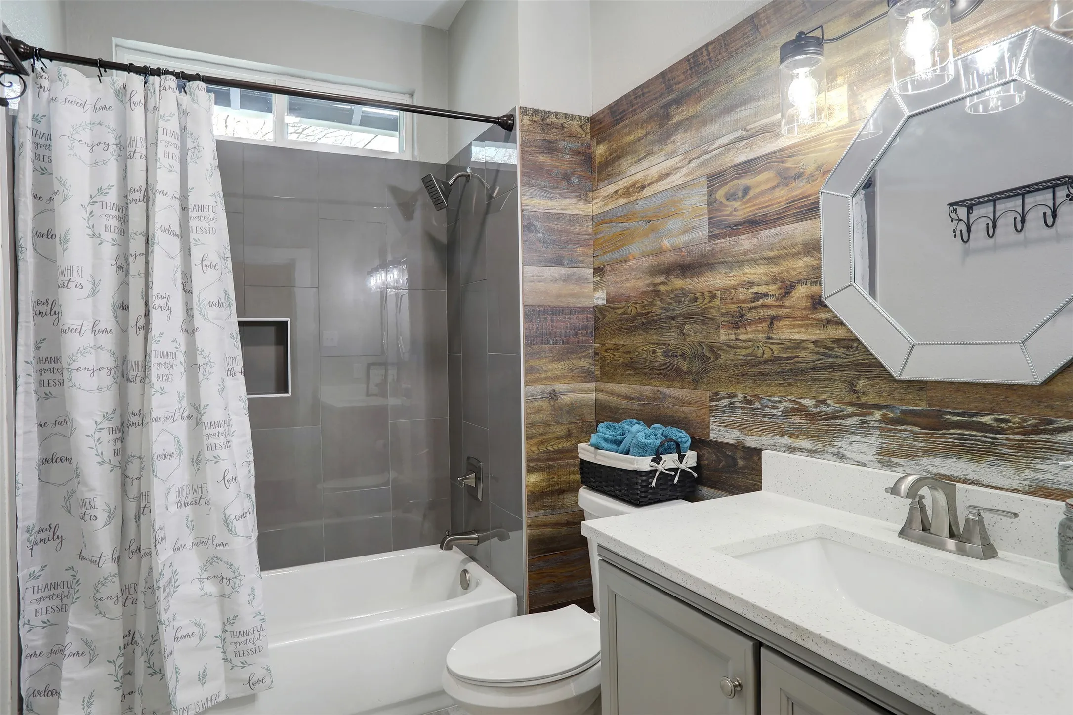 Bathroom featuring a wood-finish accent wall, gray vanity with white countertop, integrated sink, and brushed nickel faucet