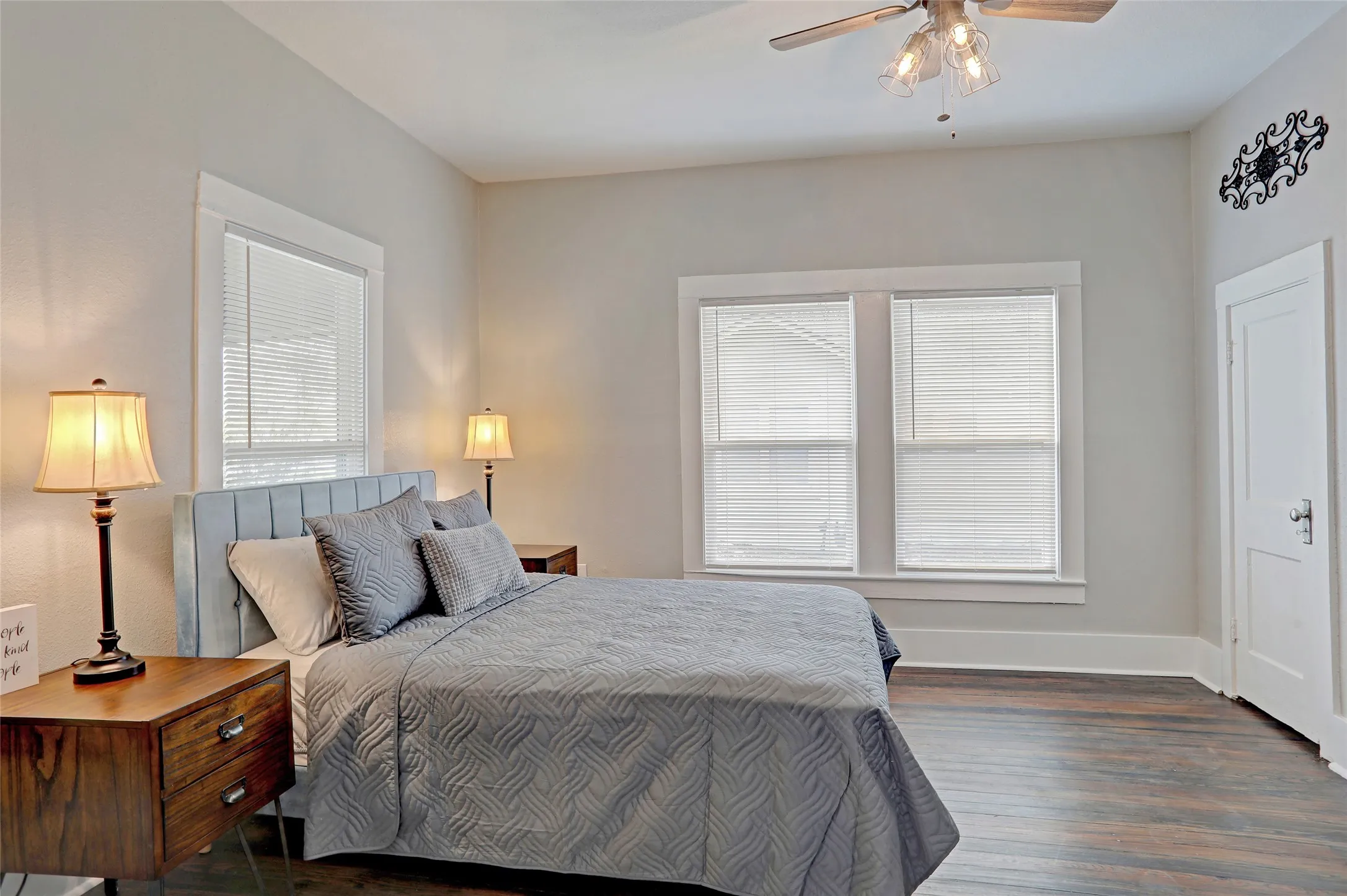 Hardwood-style flooring, white trim, multiple windows, and a ceiling fan with integrated lighting