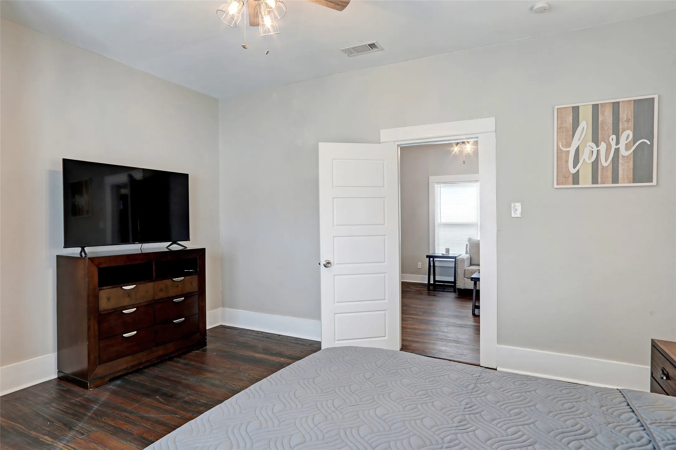 Dark wood-finish flooring, light grey wall paint, white trim, and a five-panel interior door