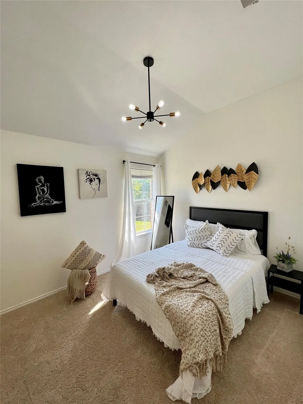 Carpeted flooring, white walls, black headboard, a window with vertical blinds, and a multi-directional light fixture