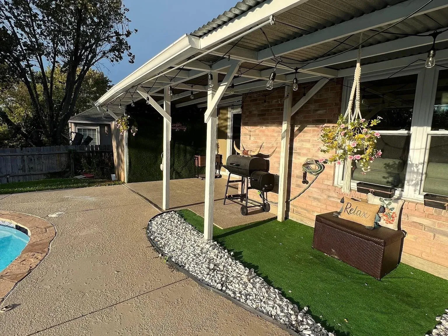 Poured concrete patio with a covered outdoor area, corrugated metal roofing, and brick exterior