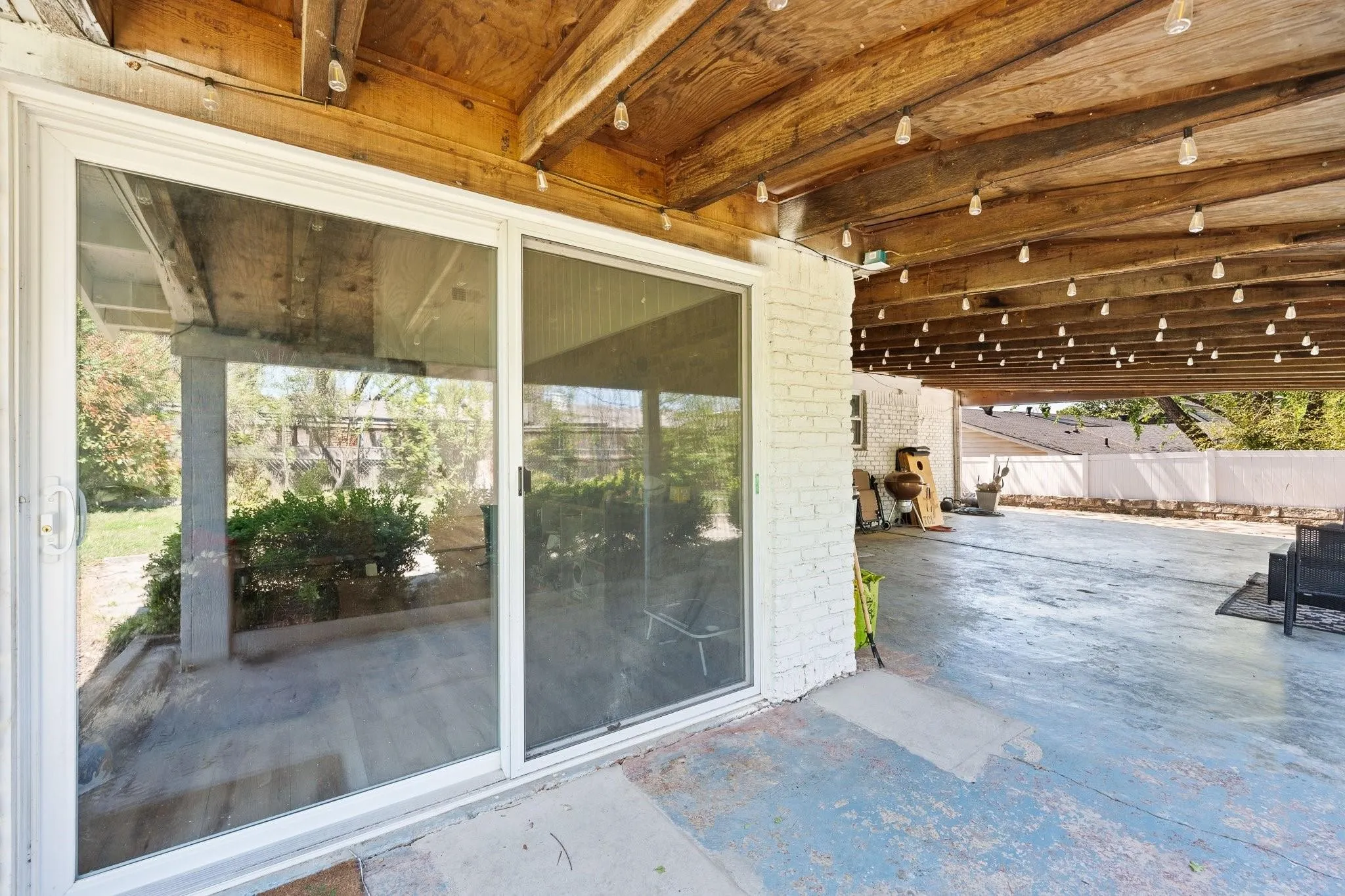 Expansive covered patio with a wood-plank ceiling, string lighting, and direct access through a sliding glass door