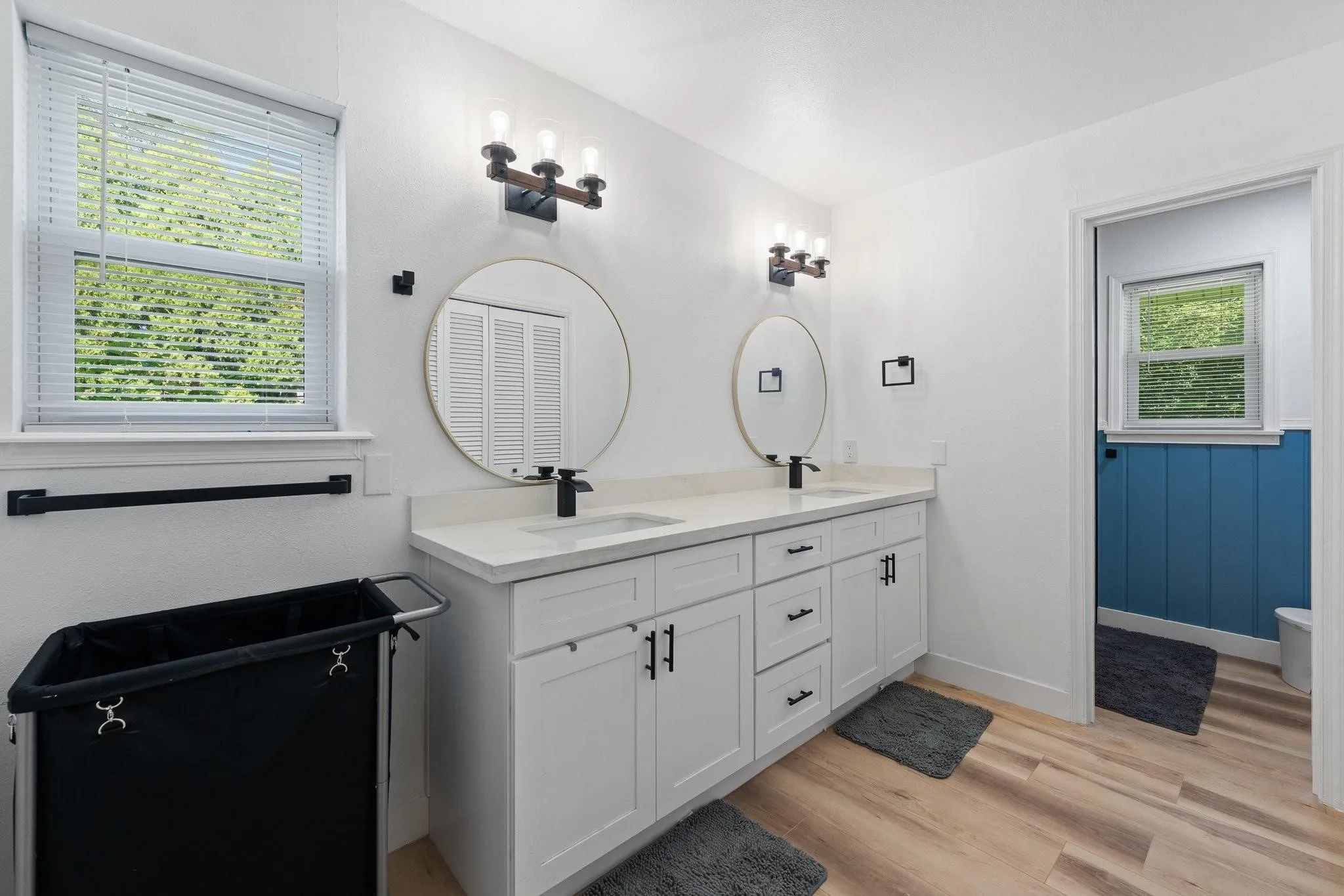 Dual vanity with white shaker-style cabinetry, matte black hardware, and integrated sinks