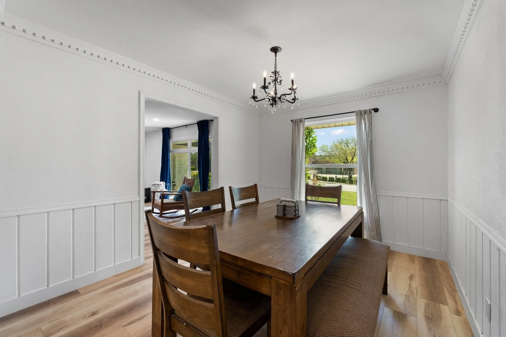 Dining area featuring crown molding, wood-finish flooring, wainscoting, and a chandelier