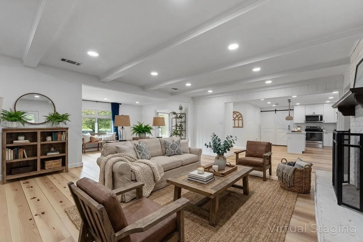 Open-concept living area featuring exposed ceiling beams, recessed lighting, wood-finish flooring, a white brick fireplace, and a barn door entry to an adjacent space