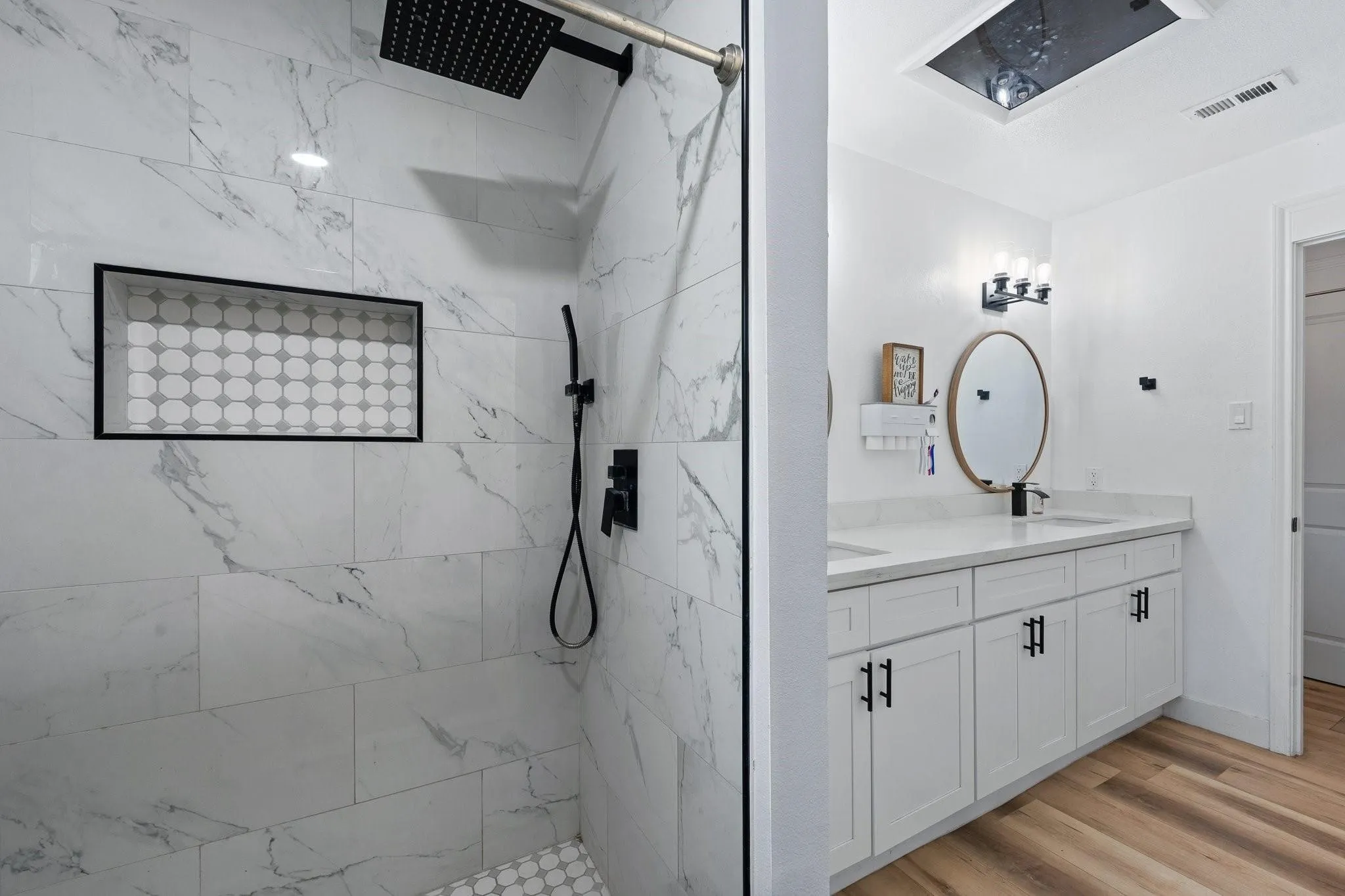 Walk-in shower with large format wall tile, black matte fixtures, and a recessed niche