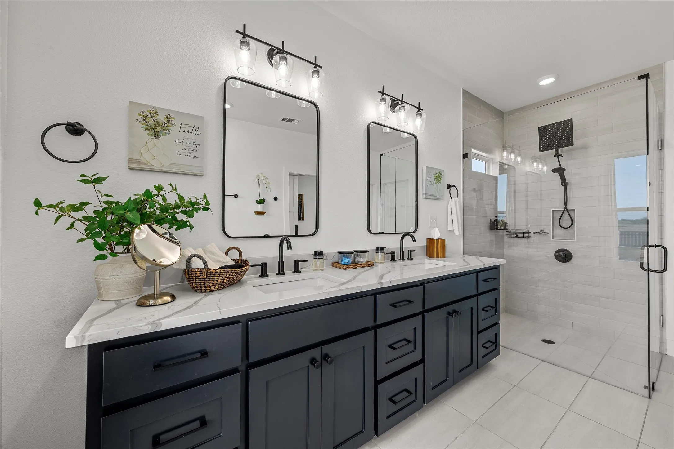 Dual vanity with stone-finish countertop, matte black fixtures, and framed mirrors