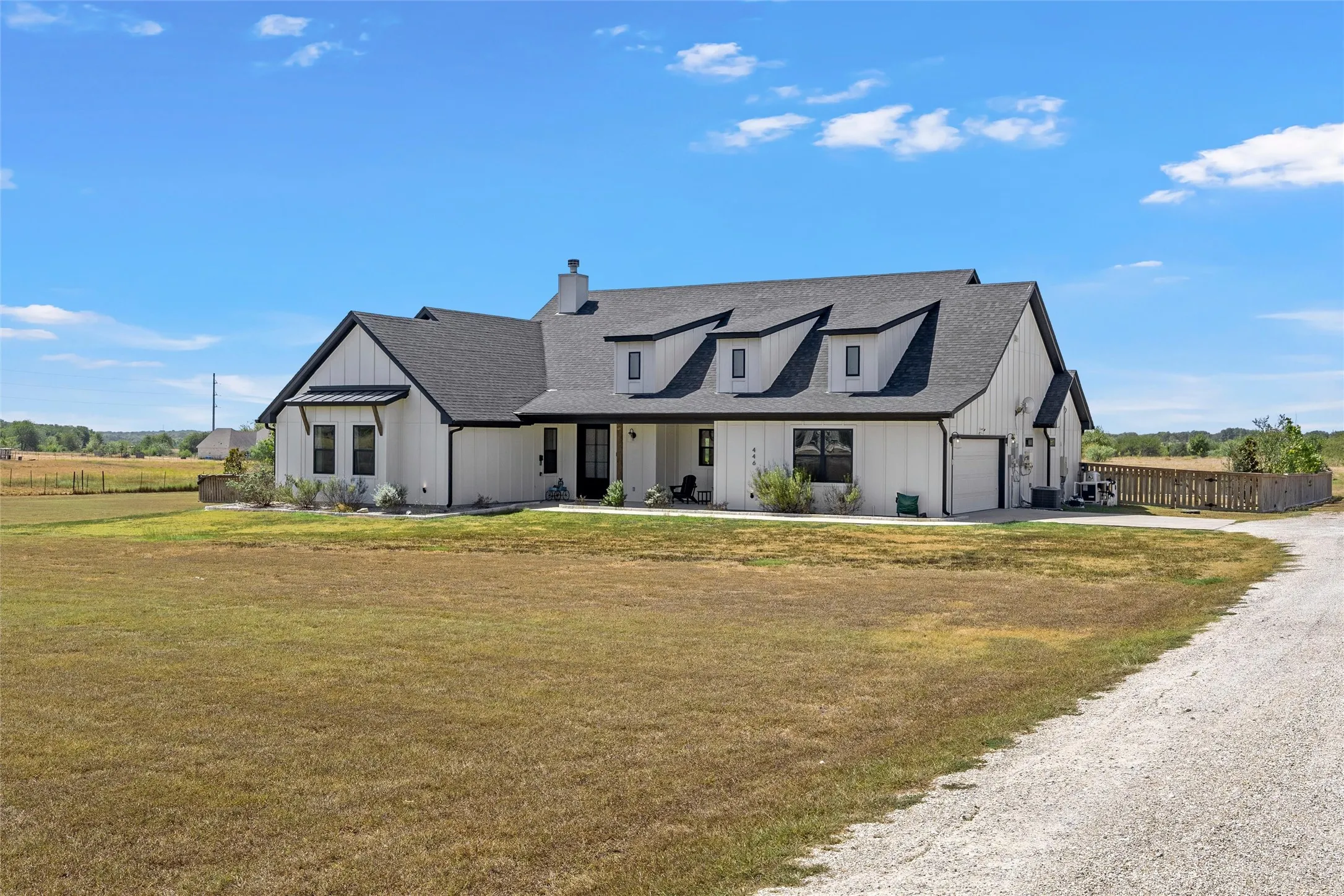 Modern farmhouse exterior with white board and batten siding, dark shingle roof, and multiple dormer windows