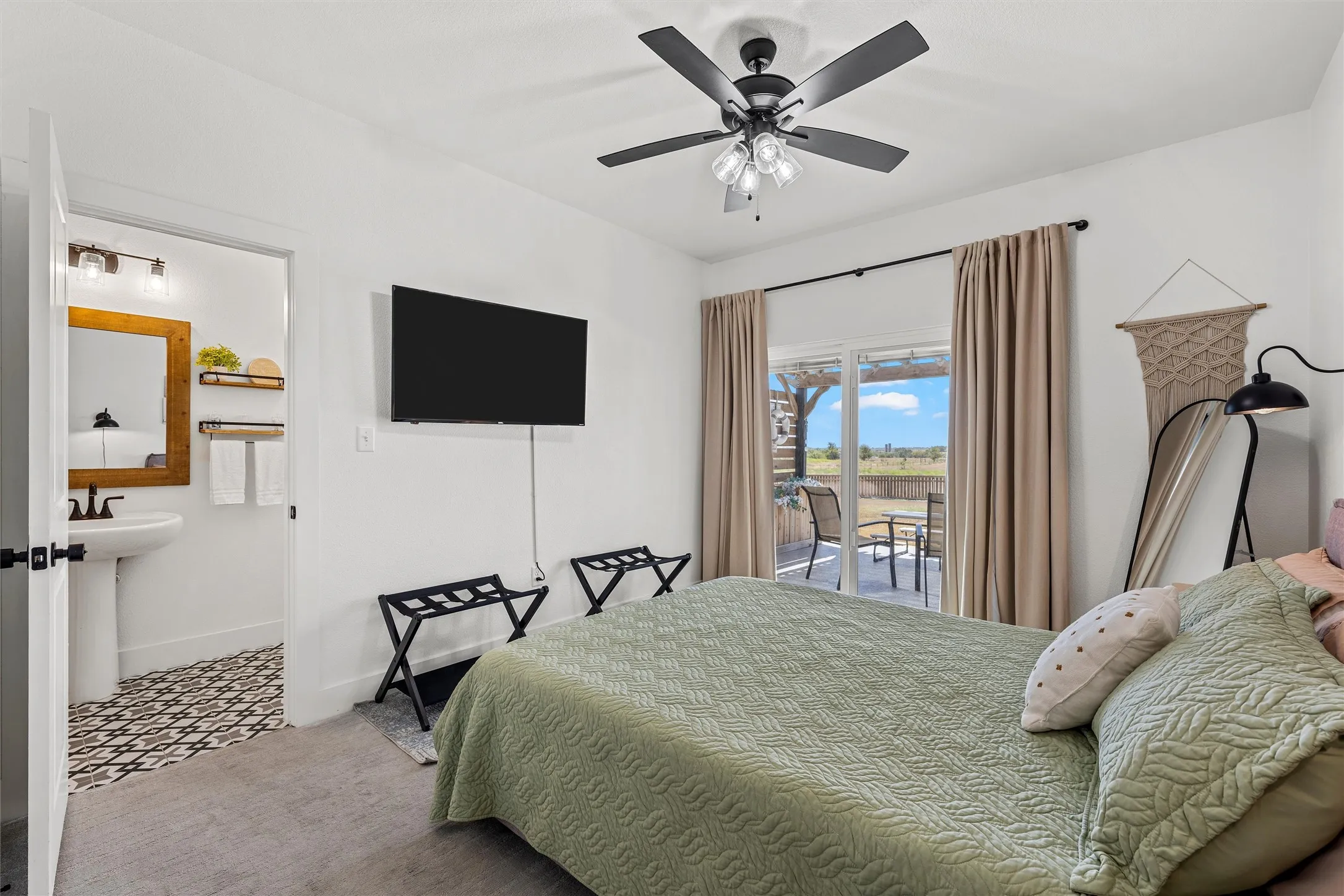 White walls featuring a ceiling fan, sliding glass door to exterior, and wall-mounted television