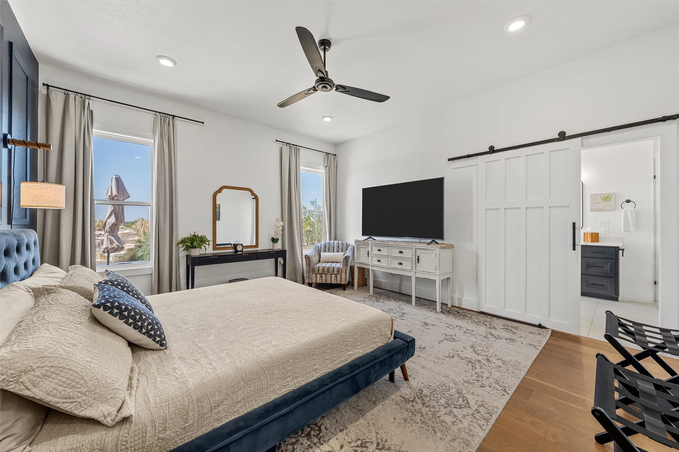 Recessed ceiling lighting, a modern ceiling fan, wood-finish flooring, and a white paneled barn door