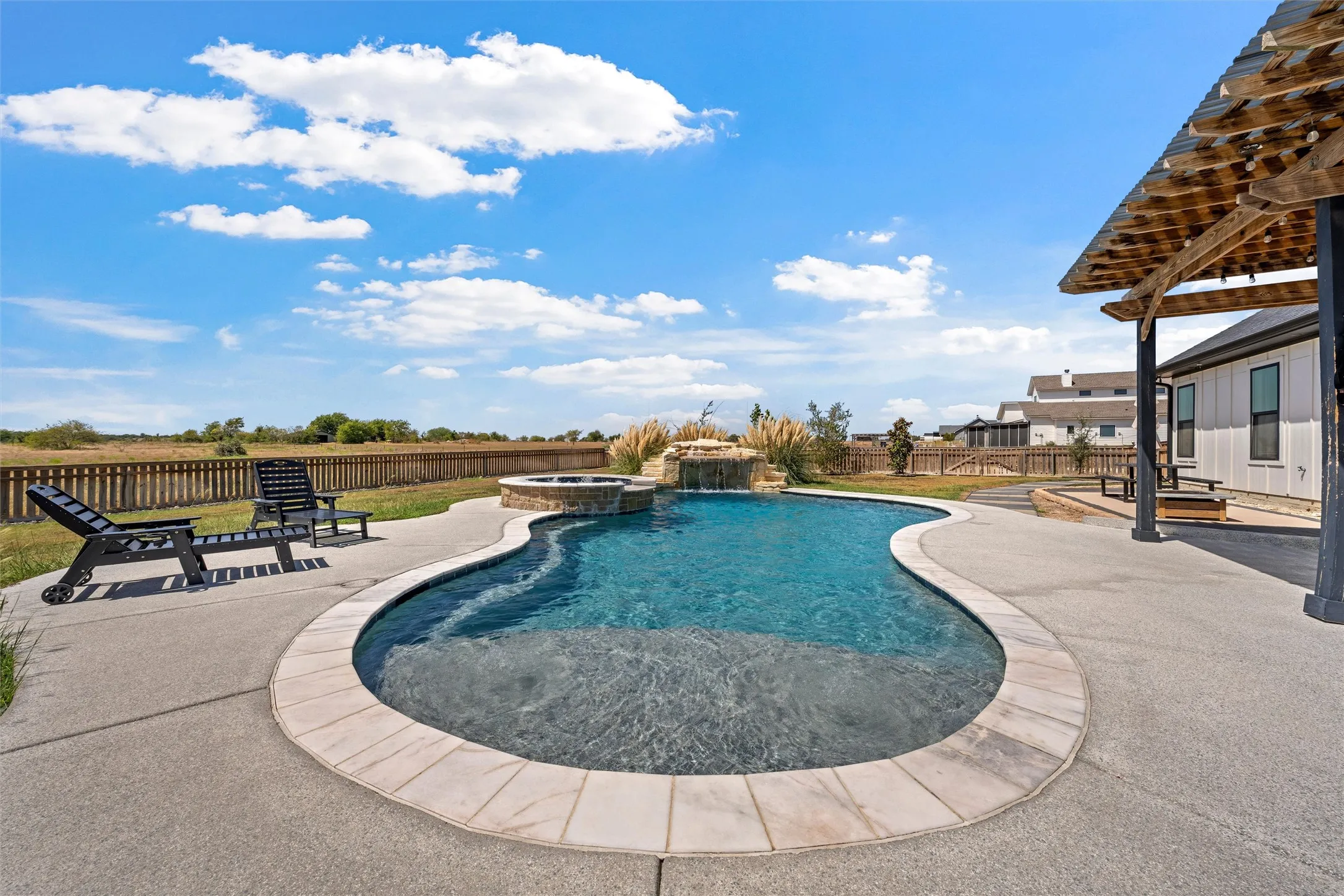 Curved swimming pool with integrated spa and waterfall feature