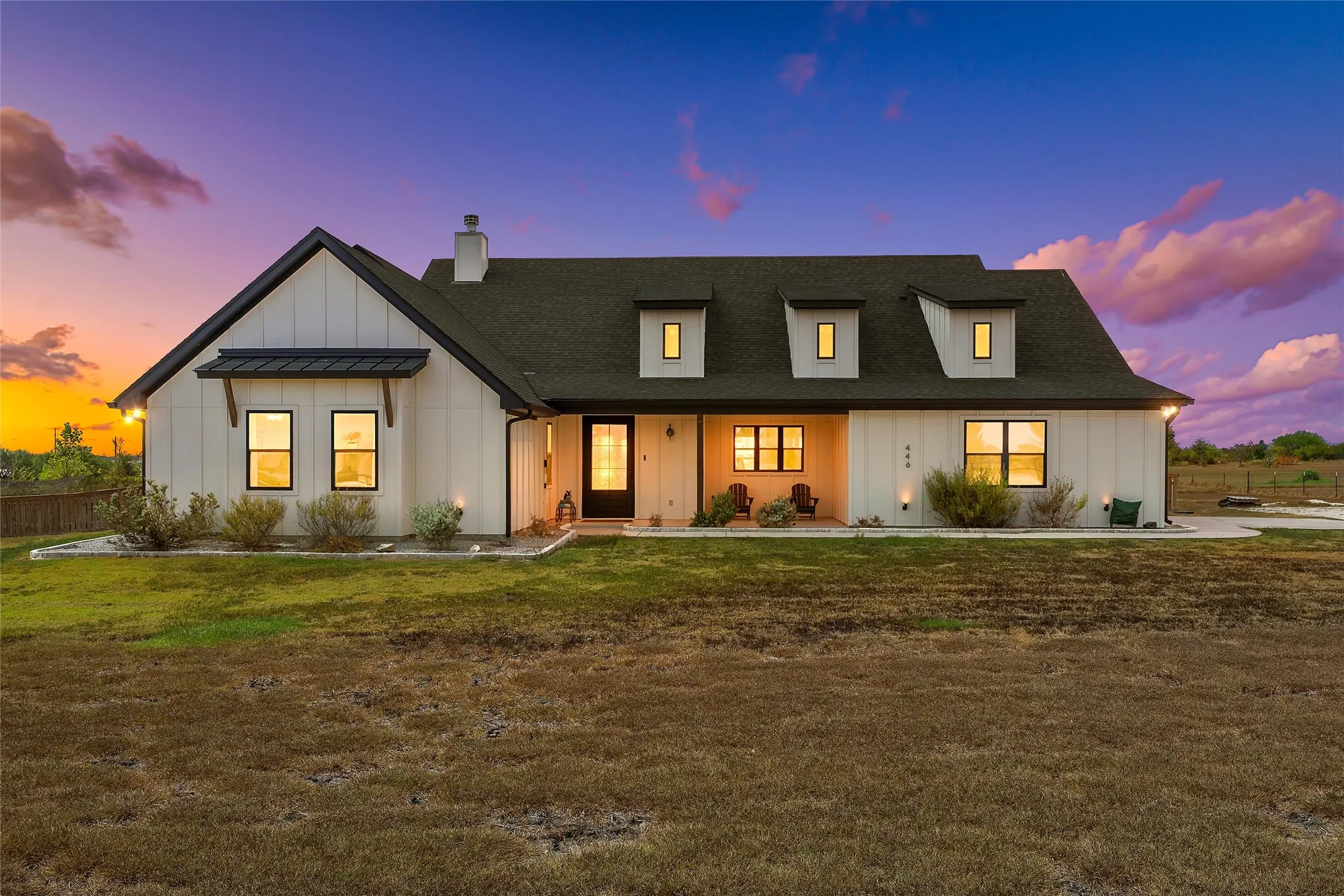 Board and batten exterior with dark trim accents, a prominent front door, and multiple dormer windows