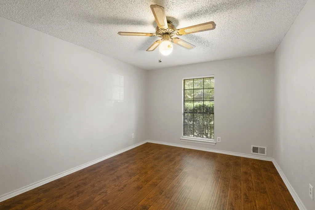 Hardwood-finish flooring, single window with blinds, ceiling fan with integrated lighting, textured walls, and white trim