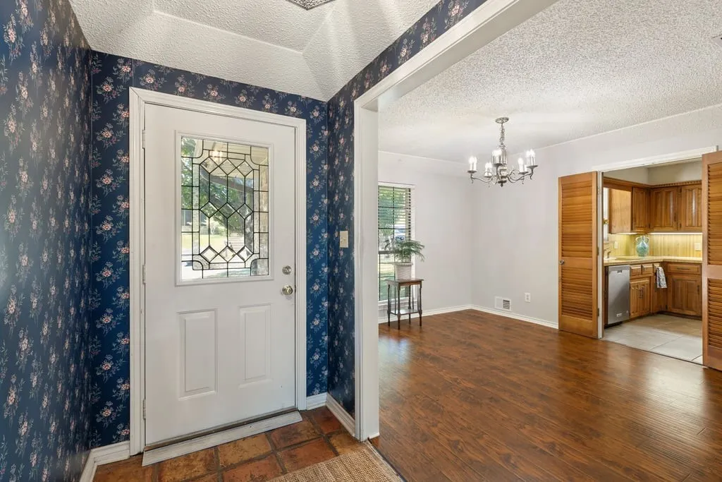 Leaded glass entry door, wood-finish flooring, chandelier lighting, and wood louvered bi-fold doors