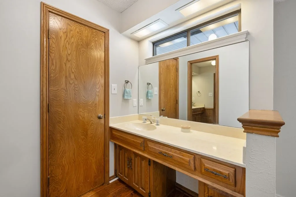 Wood-finish vanity with an integrated sink and a large wall-mounted mirror