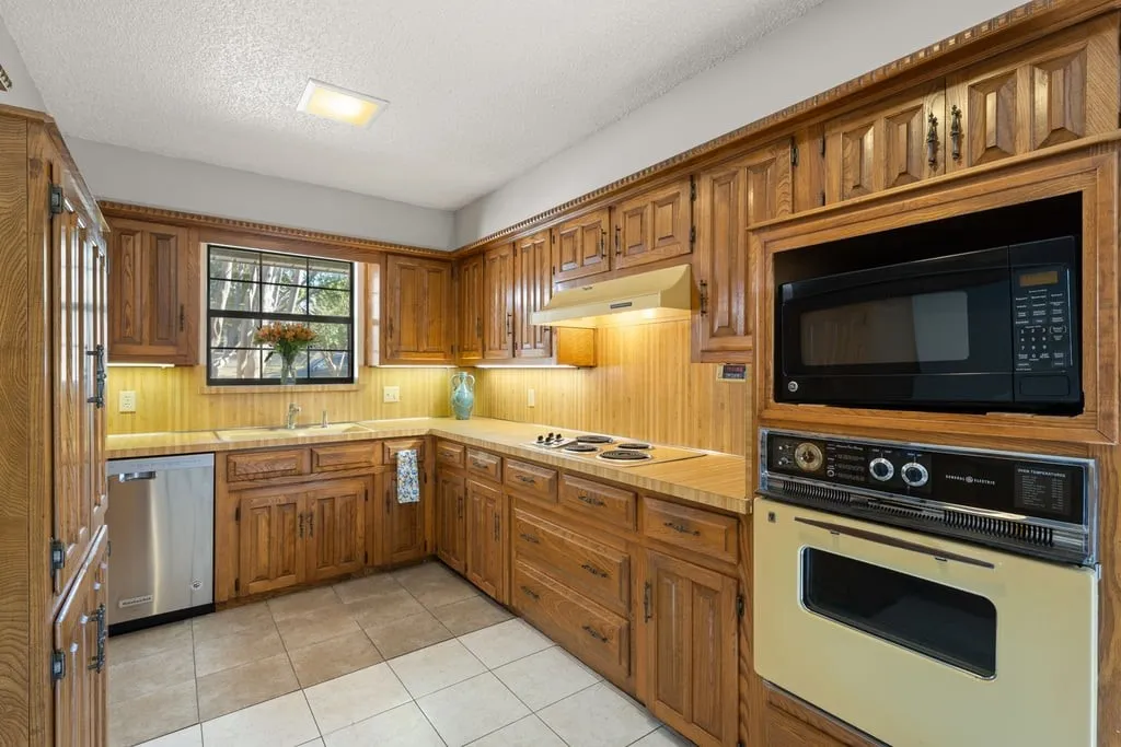 Wood cabinetry with detailed crown molding, built-in microwave, integrated wall oven, and stainless steel dishwasher