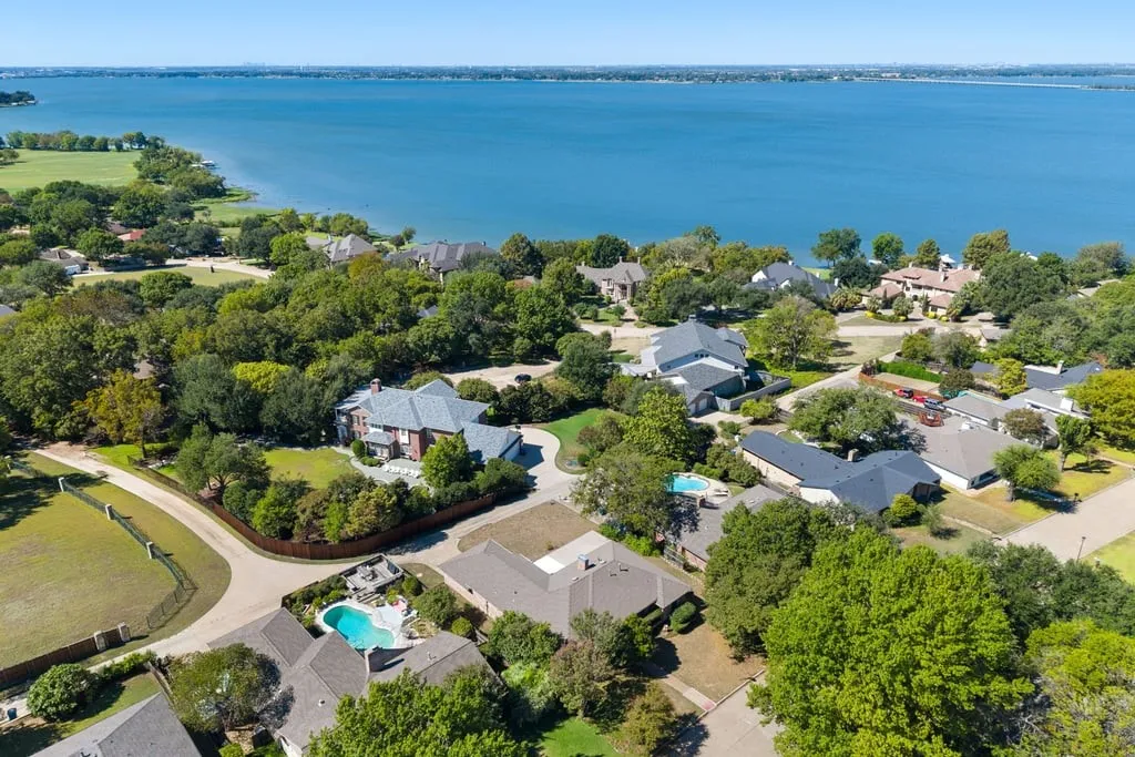 Waterfront property with extensive landscaping, mature trees, and an in-ground swimming pool