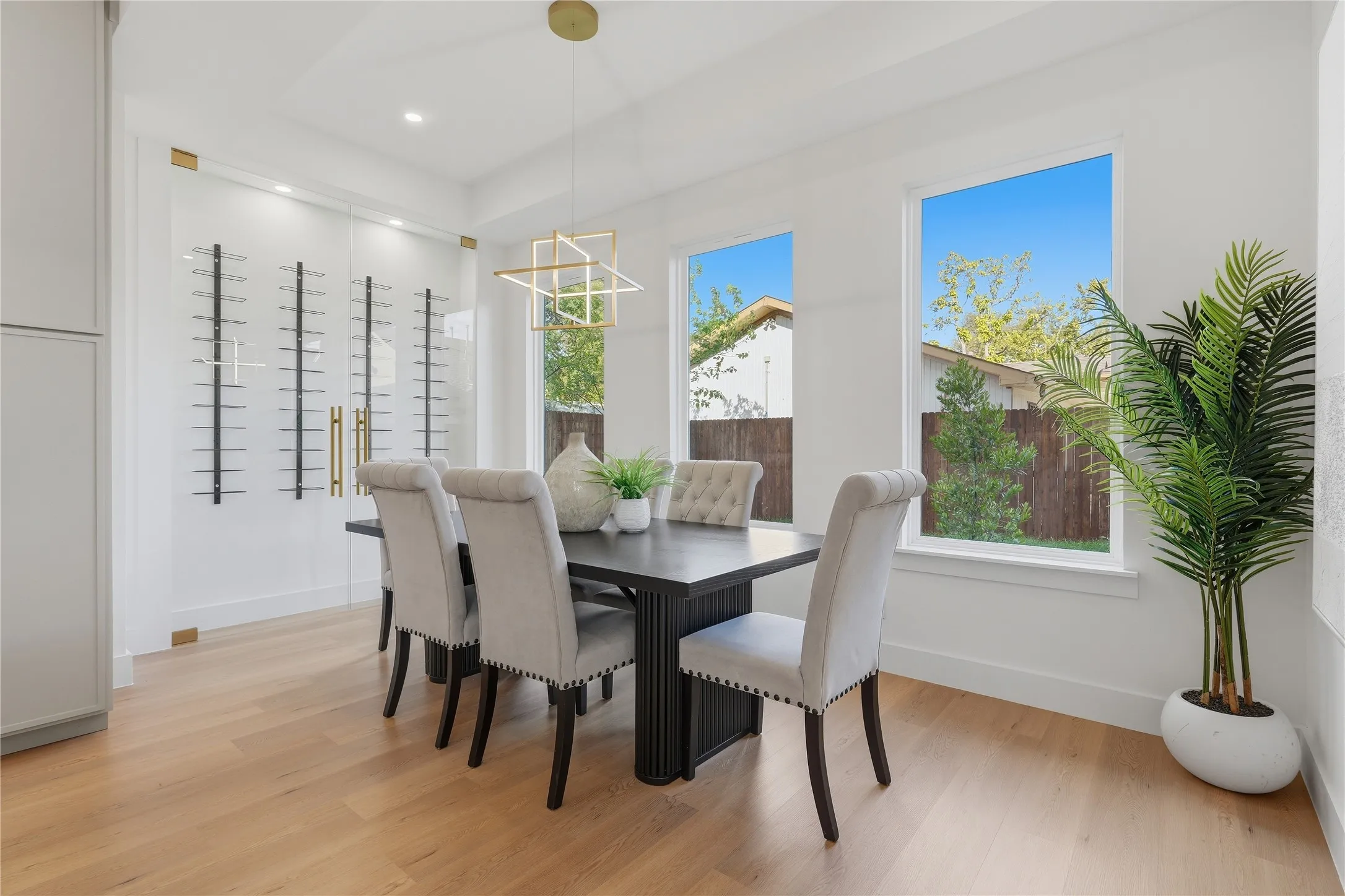 Light wood-finish flooring, white walls, recessed ceiling lighting, and a geometric chandelier