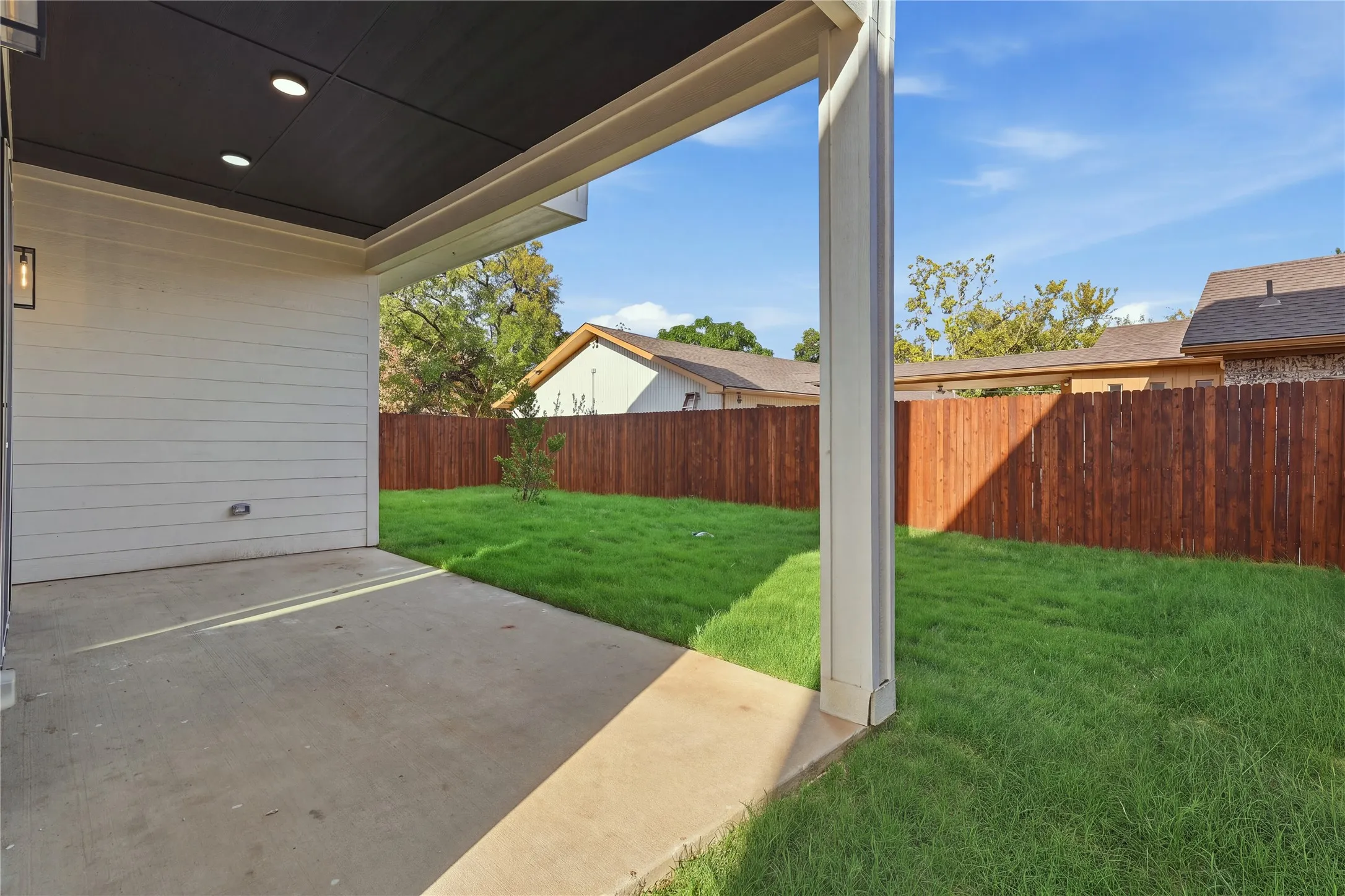 Expansive backyard featuring a freshly manicured lawn, mature landscaping, and privacy fencing