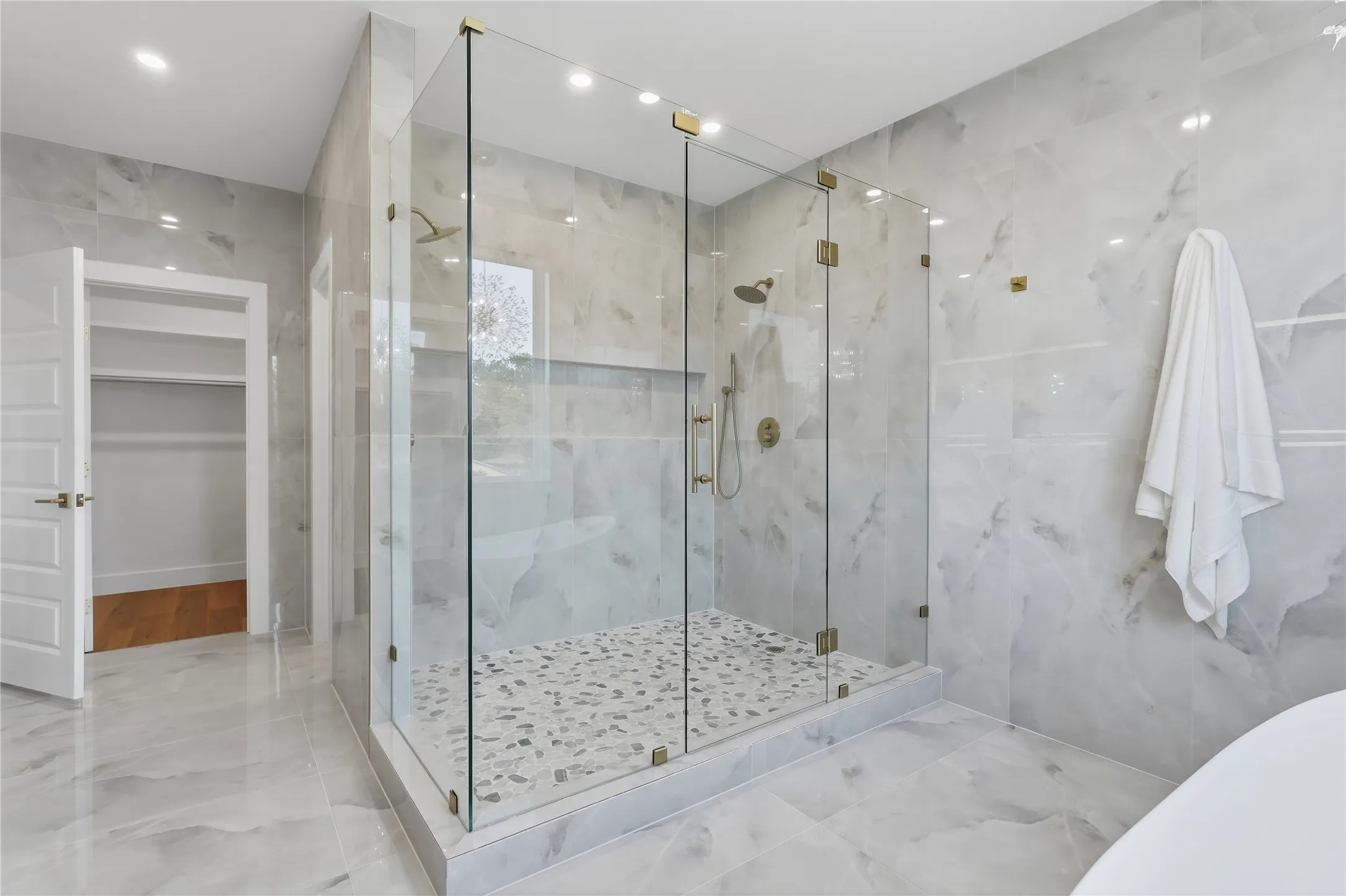 Spacious walk-in shower with clear glass enclosure and gold-toned hardware