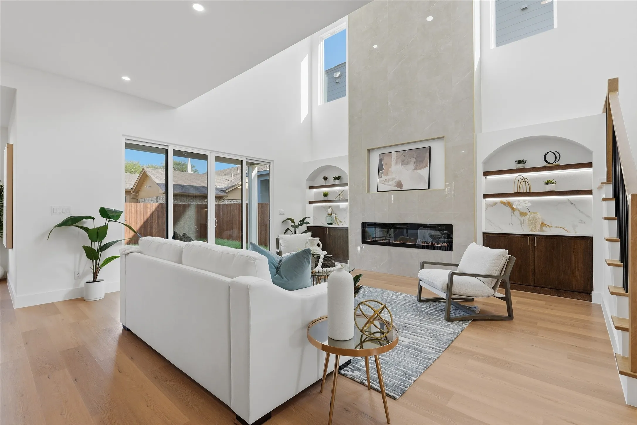 Vaulted ceilings, wood-finish flooring, full-height fireplace, built-in shelving with integrated lighting, and a sliding glass door