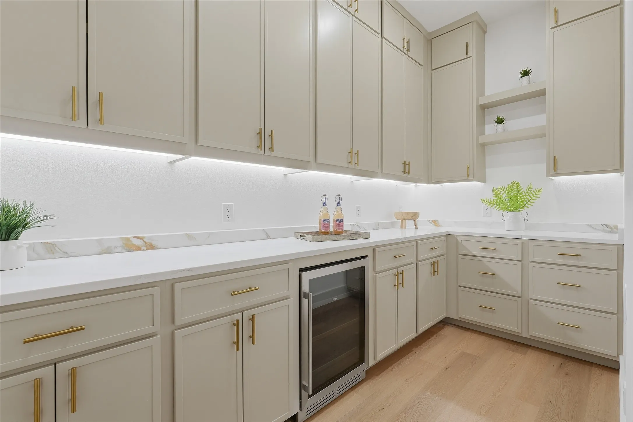 Contemporary kitchen featuring cream-painted cabinetry with brushed gold hardware, white quartz countertops, and a full-height white subway tile backsplash