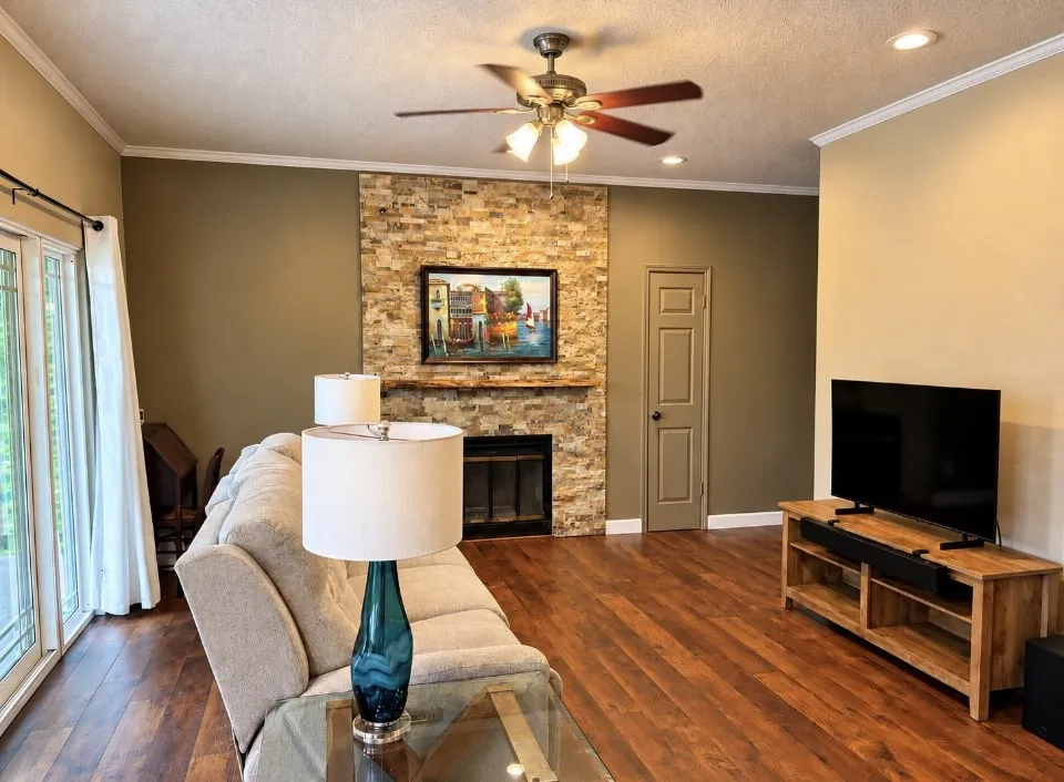 Spacious living area featuring wood-finish flooring, a stone-clad fireplace, and recessed lighting