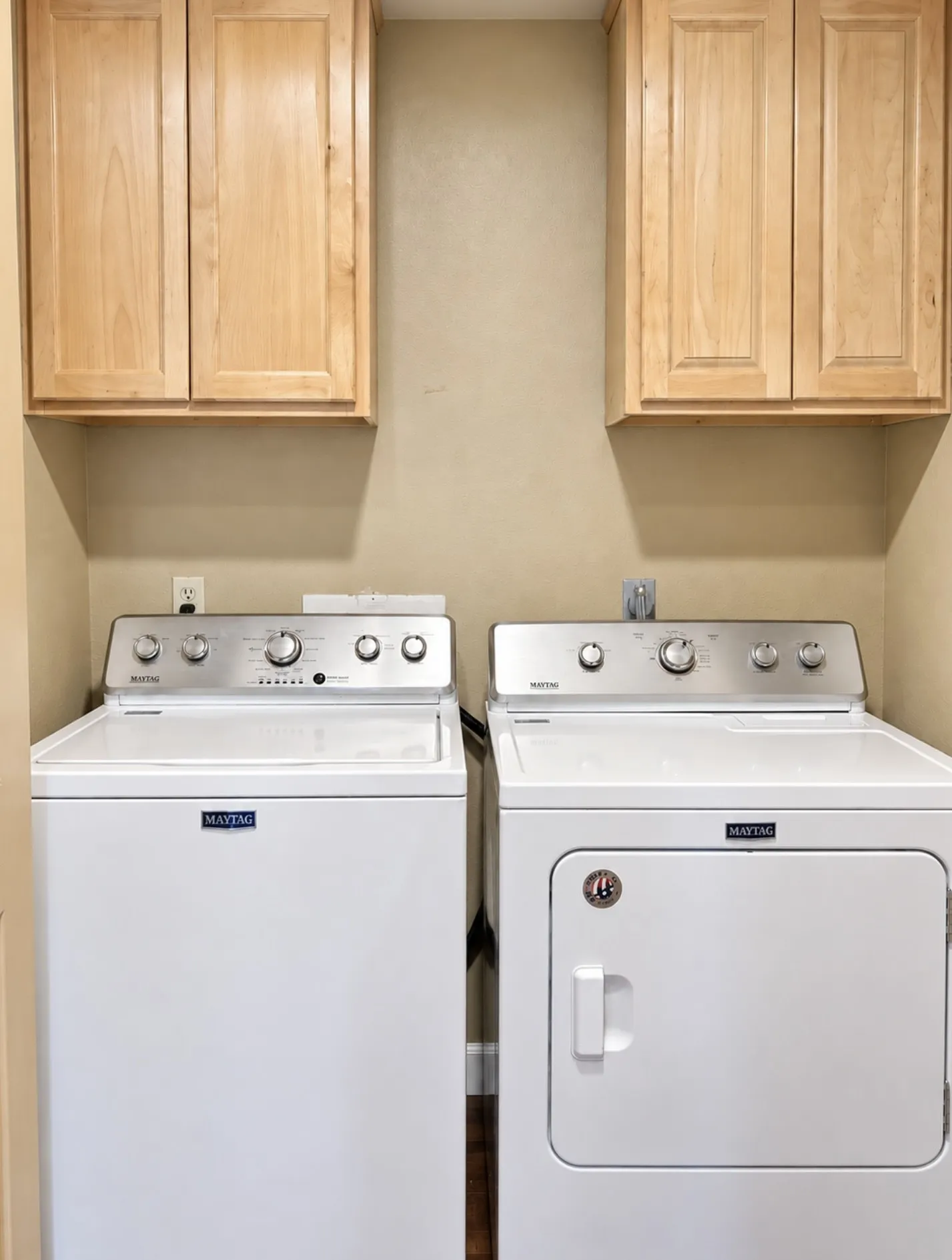 Laundry area with light wood-finish cabinetry and a neutral wall color
