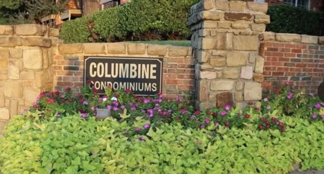 Stone and brick entrance wall with vibrant landscaping