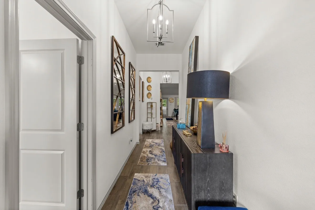 Hallway featuring wood-finish flooring, white walls, and a decorative pendant light fixture