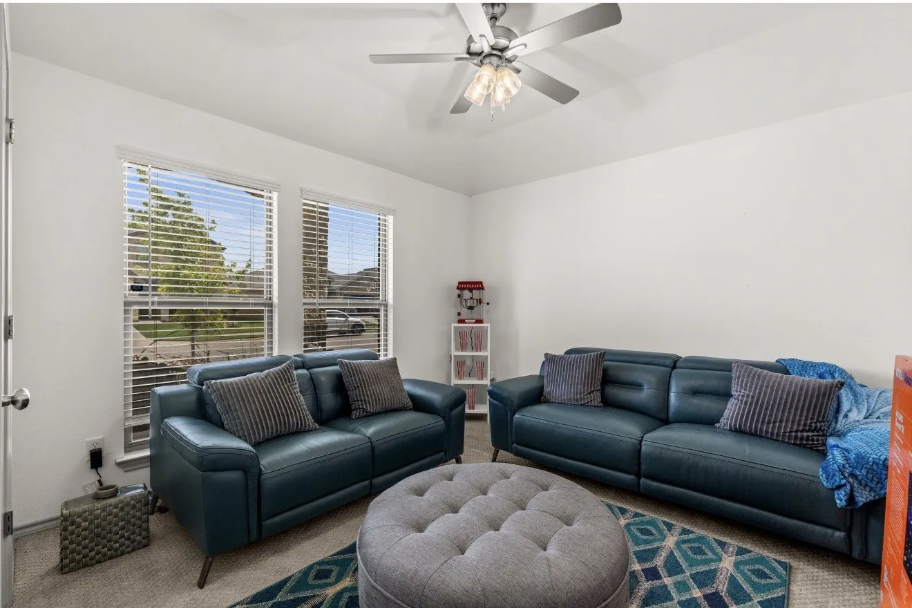 White painted walls, two large windows with blinds, a ceiling fan with integrated lighting, and carpeted flooring