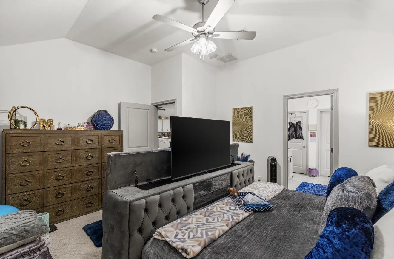 Vaulted ceiling with a ceiling fan, white painted walls, and wood-paneled doors