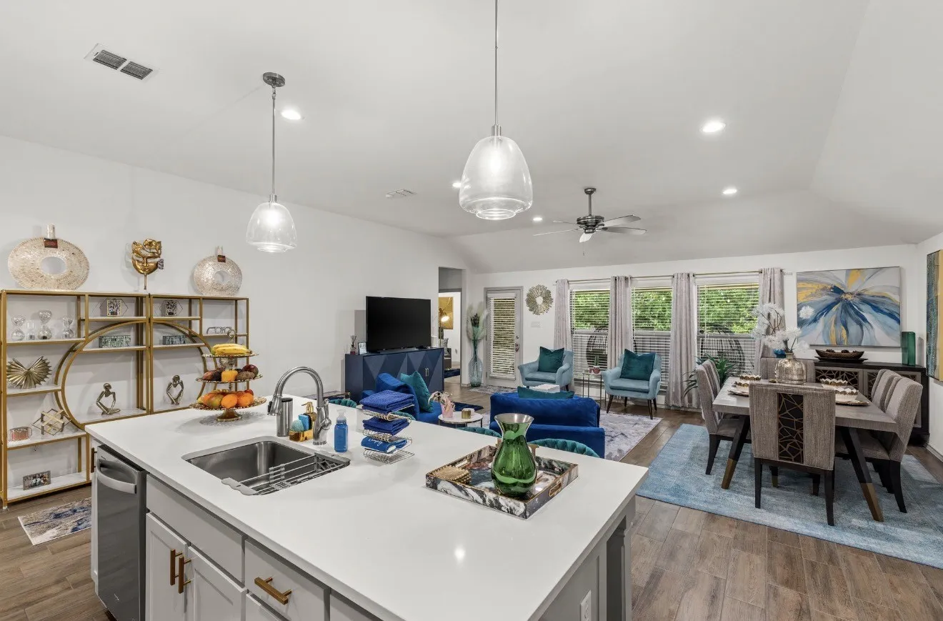 Open-concept living area featuring a kitchen island with sink, pendant lighting, wood-finish flooring, and multiple windows