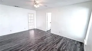 Wood-finish flooring, white walls, and a ceiling fan with integrated lighting
